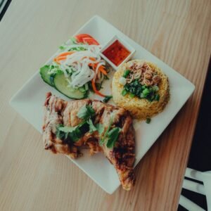 Savory fried chicken with rice, salad, and sauce on a white plate. Perfect food photography.