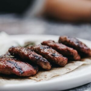 Close-up of grilled beef patties served on a tortilla with rice and vegetables, showcasing a delicious meal.