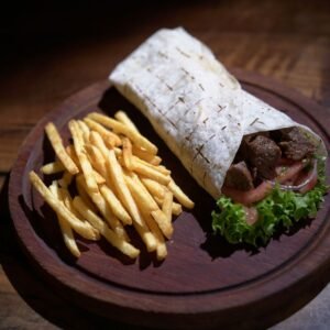 Tasty wrap with juicy meat and fresh fries served on a wooden plate.